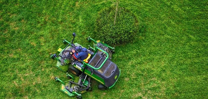 green and black ride on lawn mower on green grass field during daytime